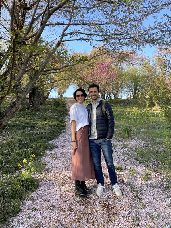 Angie y Juan en un sendero cubierto de pétalos de flor de cerezo.